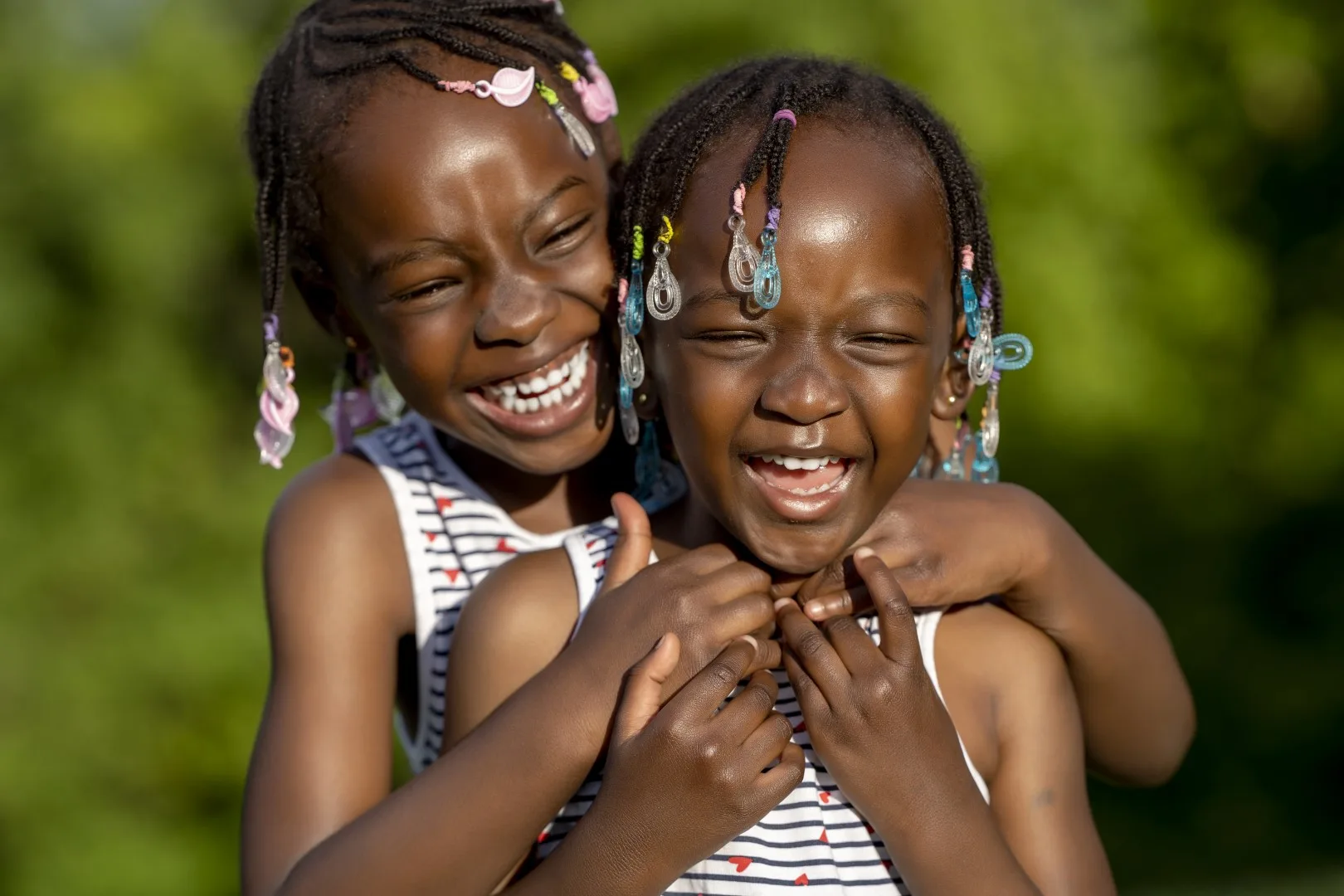 Two smiling girls embracing outdoors